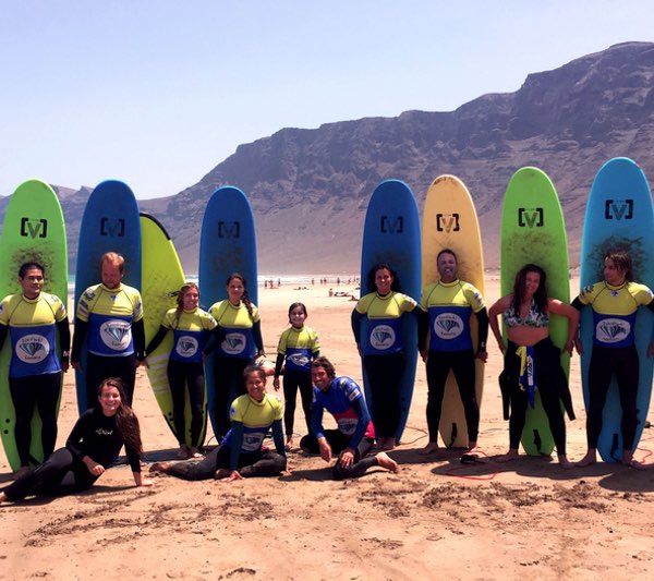 grupo de alumnos dando clases de surf en la playa de famara